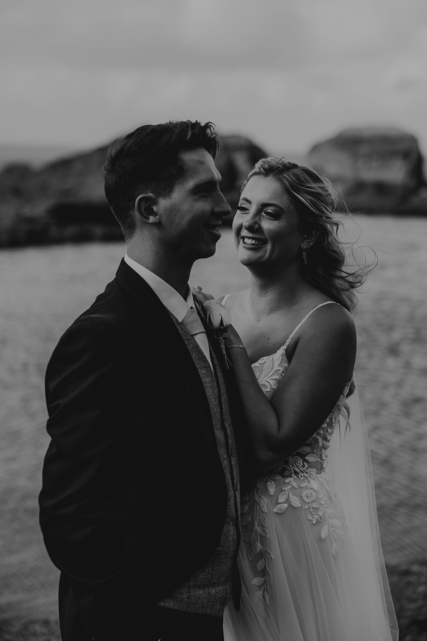 Intimate black and white wedding portraits captured against a seaside backdrop.