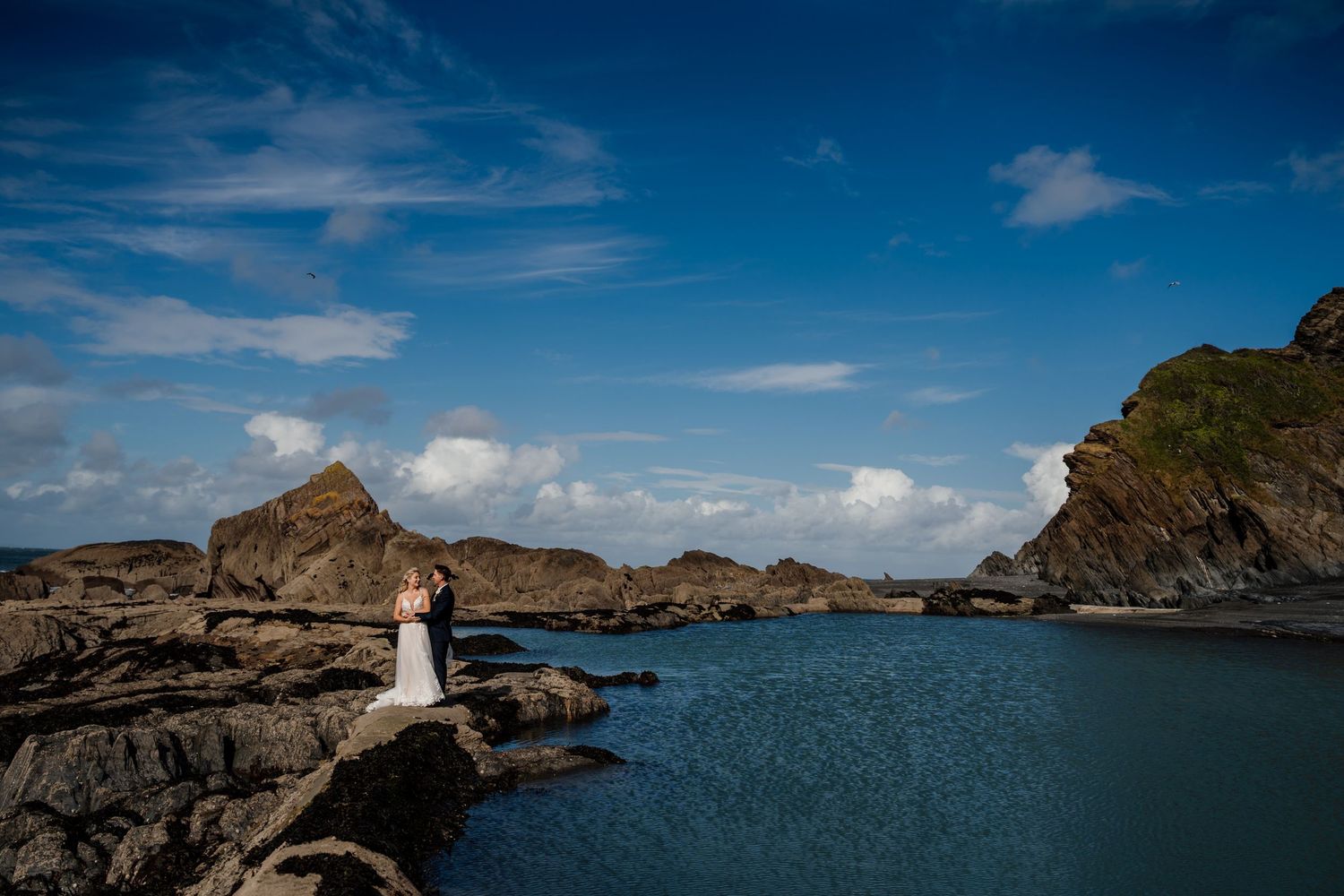 Panoramic view of a rugged coastline with dramatic cliffs and blue ocean waters under a bright sky.