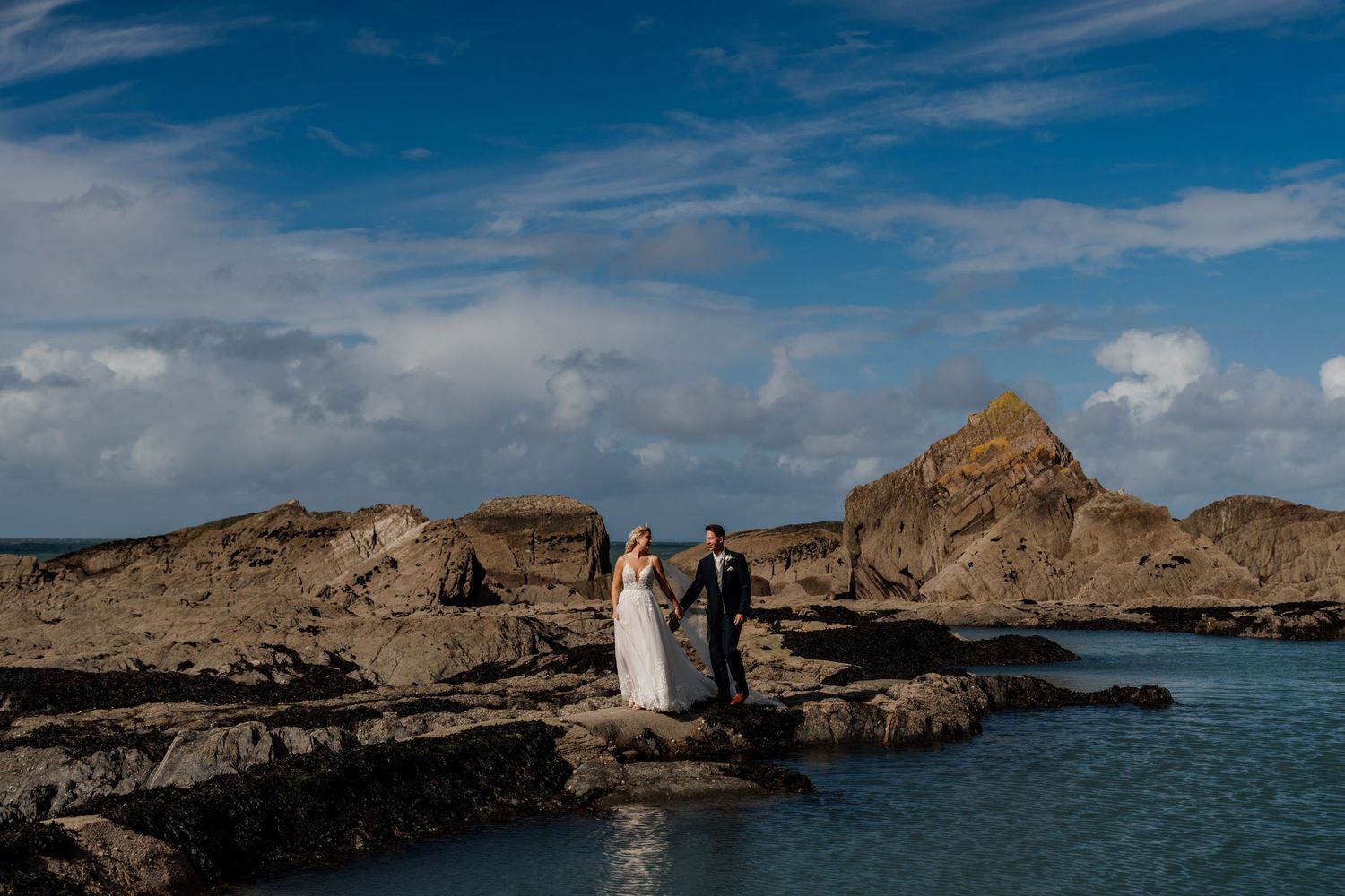 Wide angle landscape shot of coastal cliffs and modern wedding venue by the ocean.