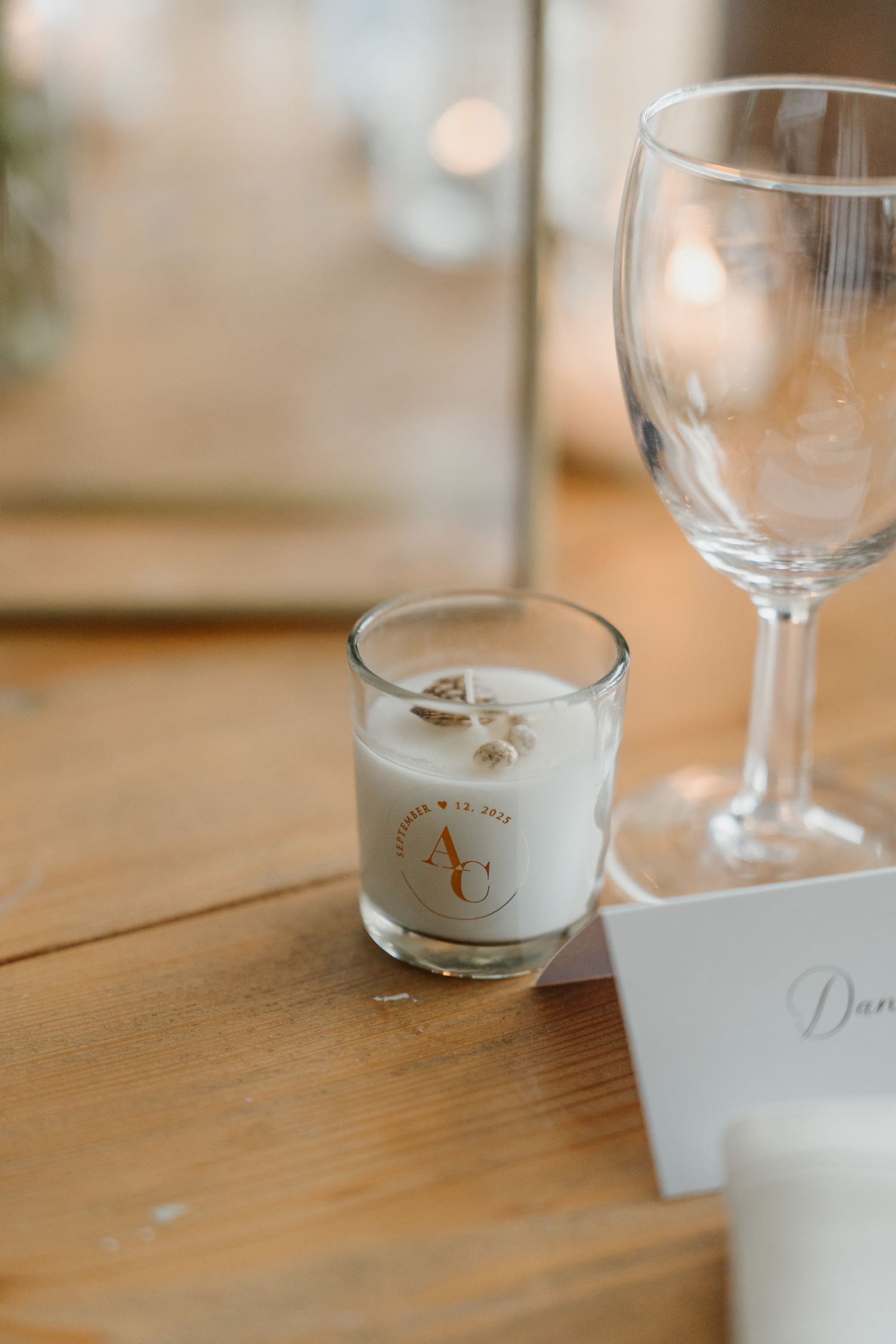 Wedding reception table settings with elegant glassware and place cards on rustic wooden tables.