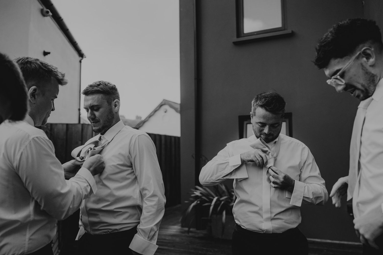 Black and white candid photo of groomsmen getting ready before the ceremony.