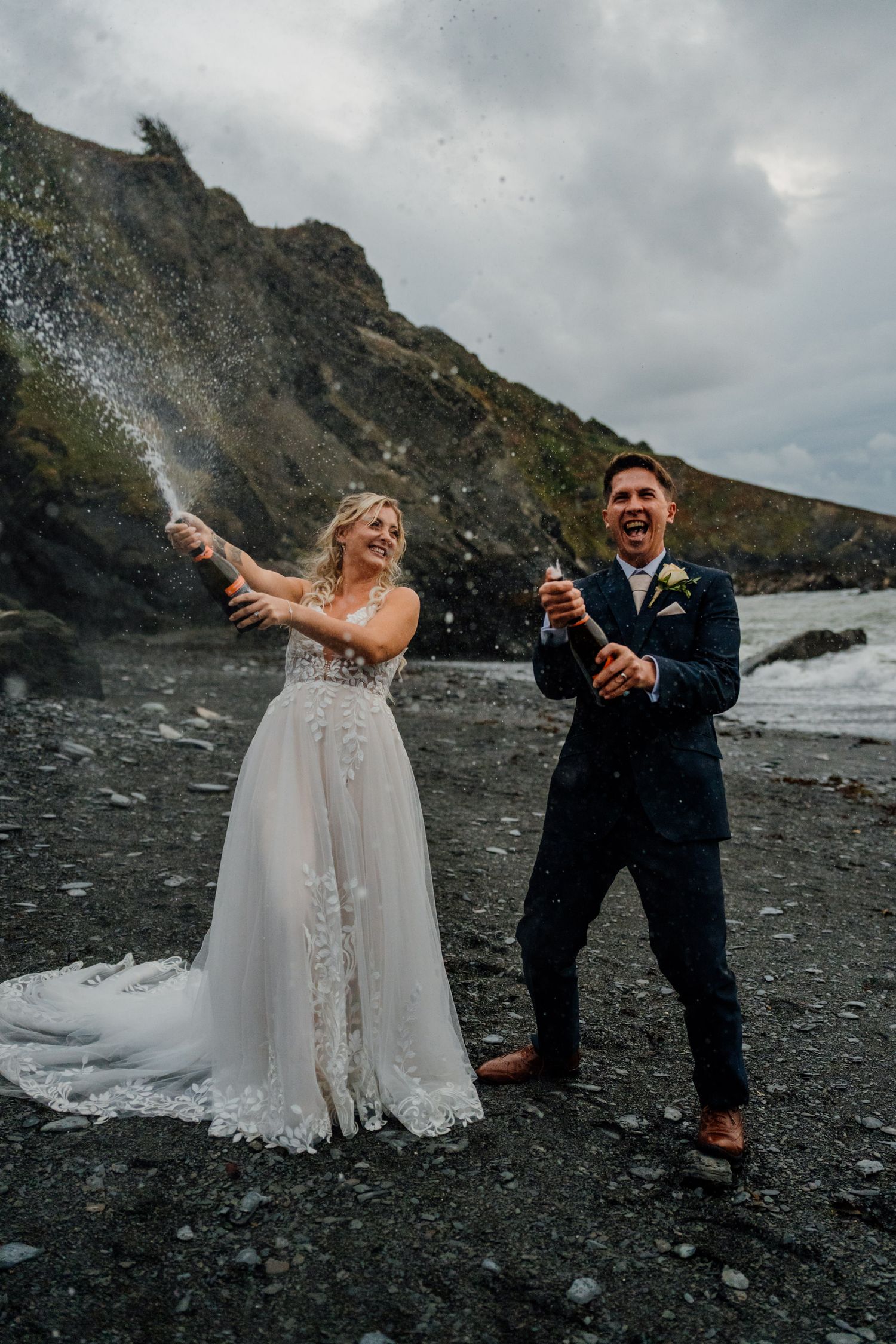 Happy couple celebrating and laughing together on a dramatic rocky coastline.