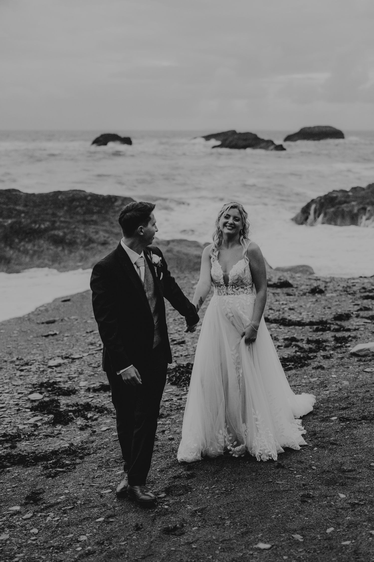 Black and white wedding photos of a couple walking along a dramatic rocky coastline.