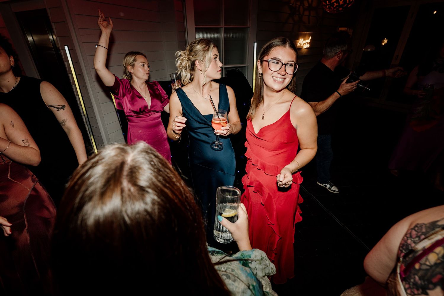 Wedding guests dancing and celebrating on a dark dance floor at a reception party.