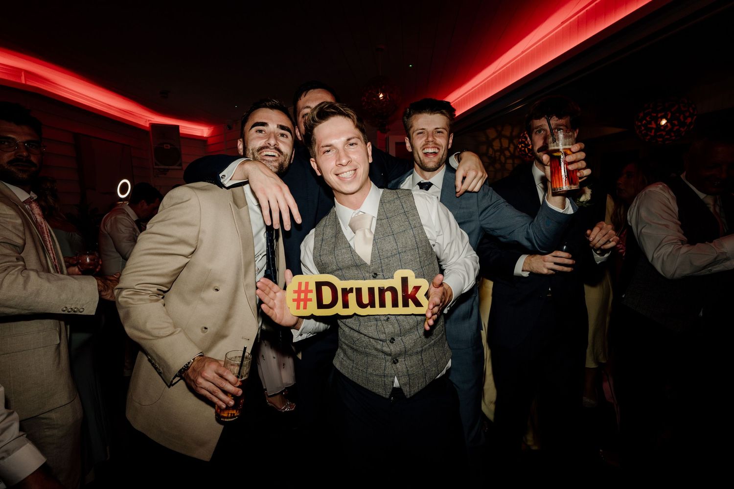 Wedding reception party scene with a neon sign and festive atmosphere.