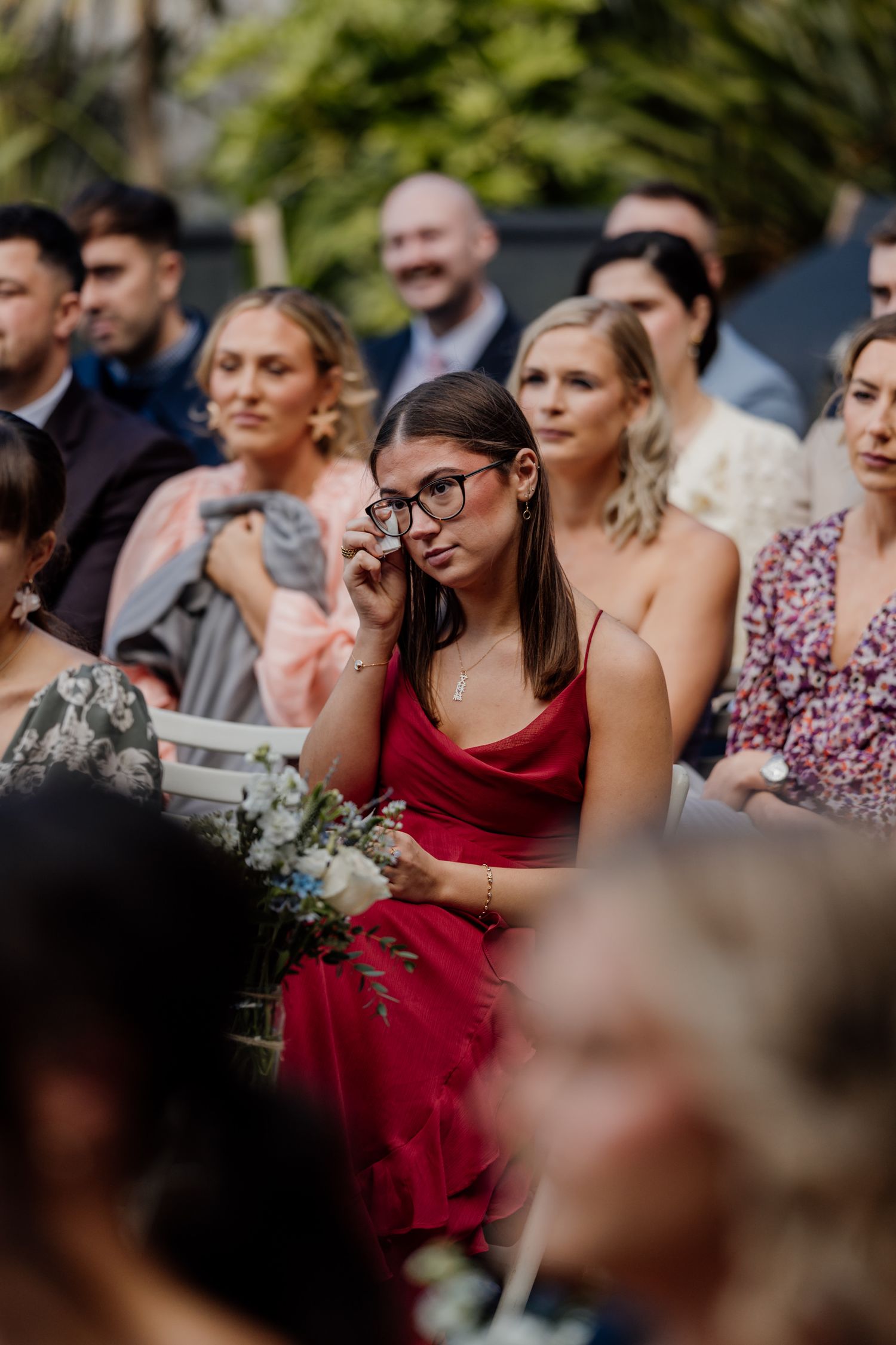 Wedding guests in formal attire watching ceremony with emotional expressions.