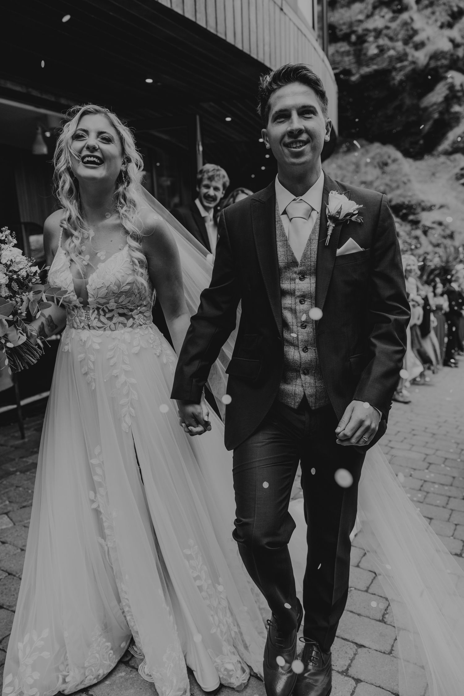 A joyful outdoor wedding celebration captured in black and white showing candid moments of laughter and happiness.