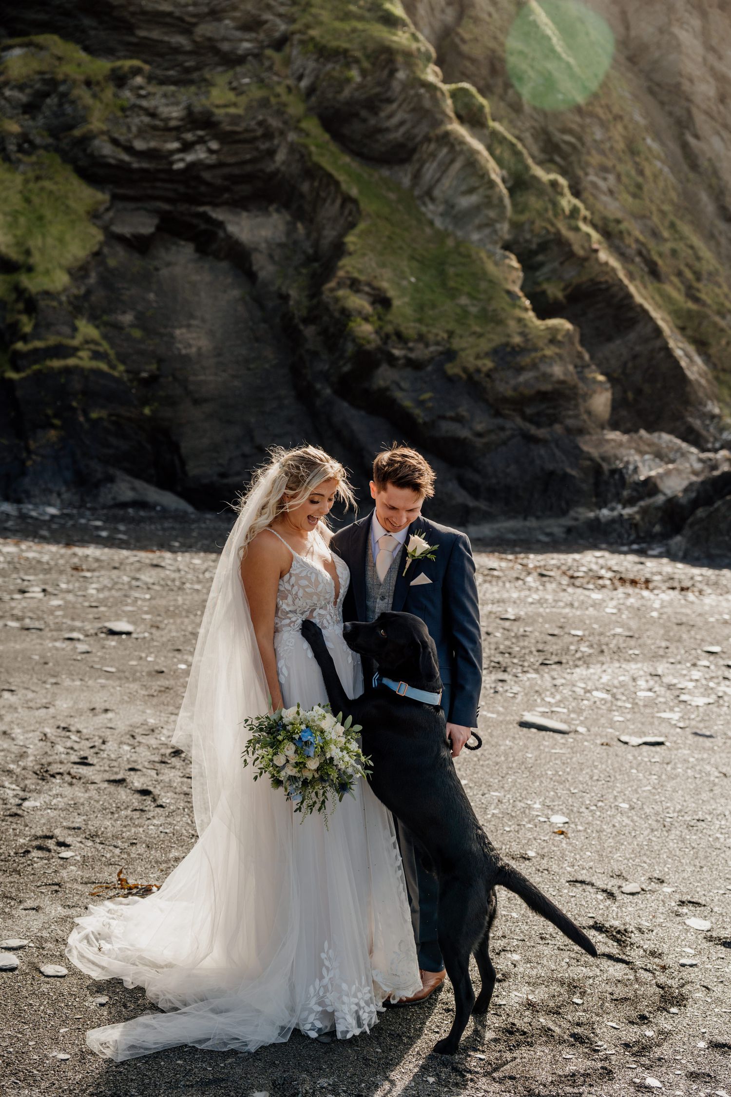 Couple sharing intimate moments on a rocky beach during a wedding photo session.