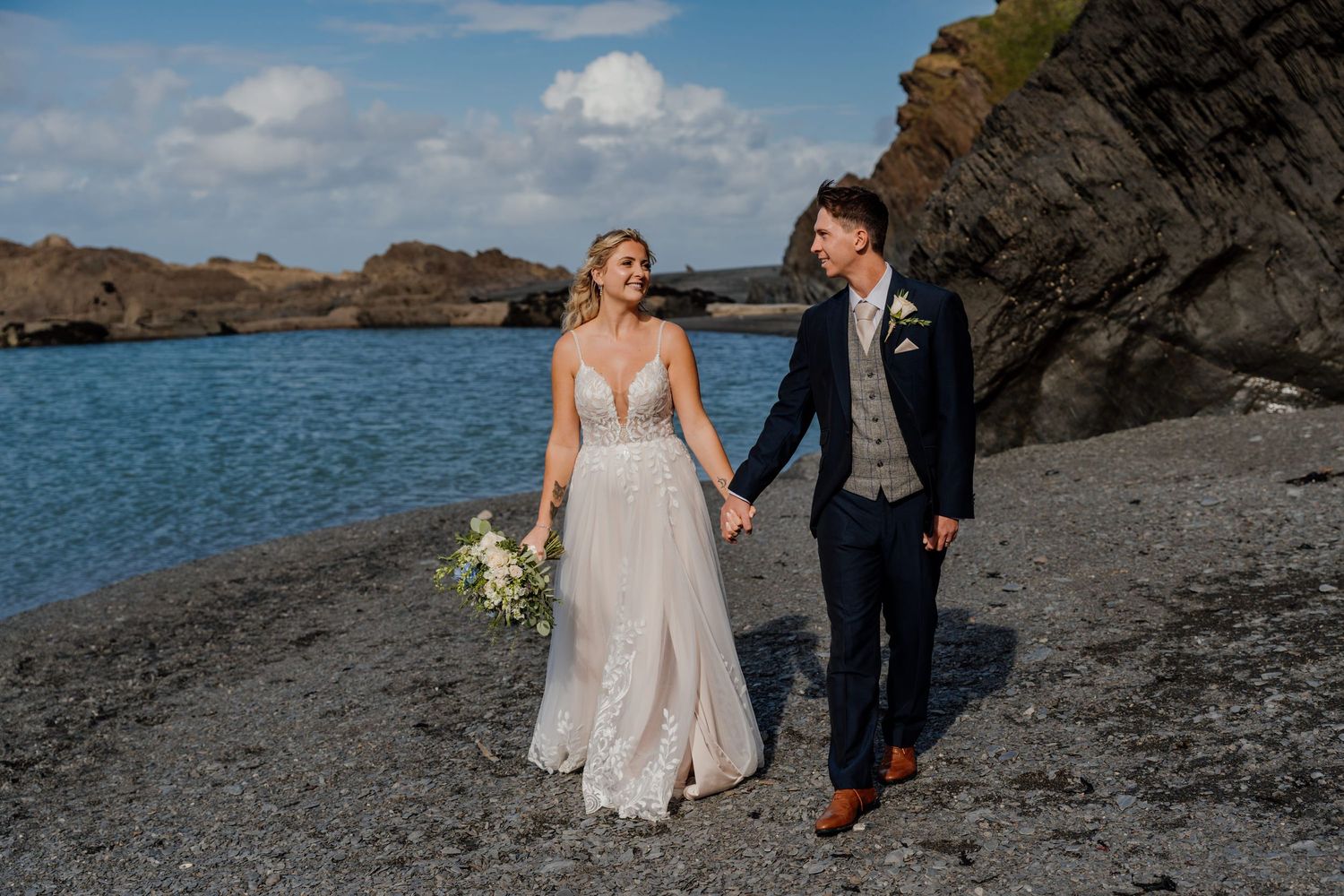 Beachside wedding portraits with scenic coastal cliffs in the background.