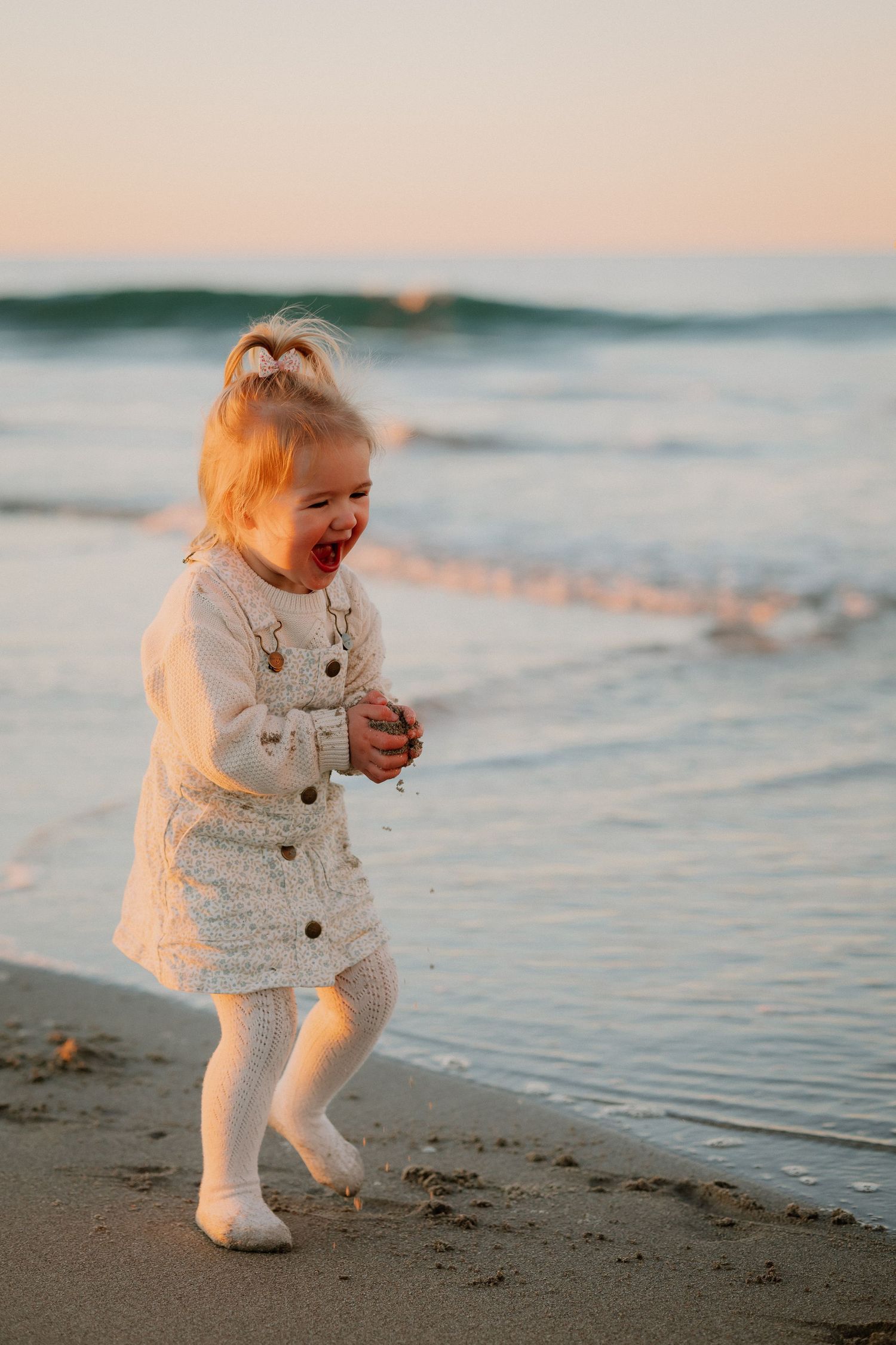 A tender moment captured at sunset by the ocean as warm golden light illuminates their faces.