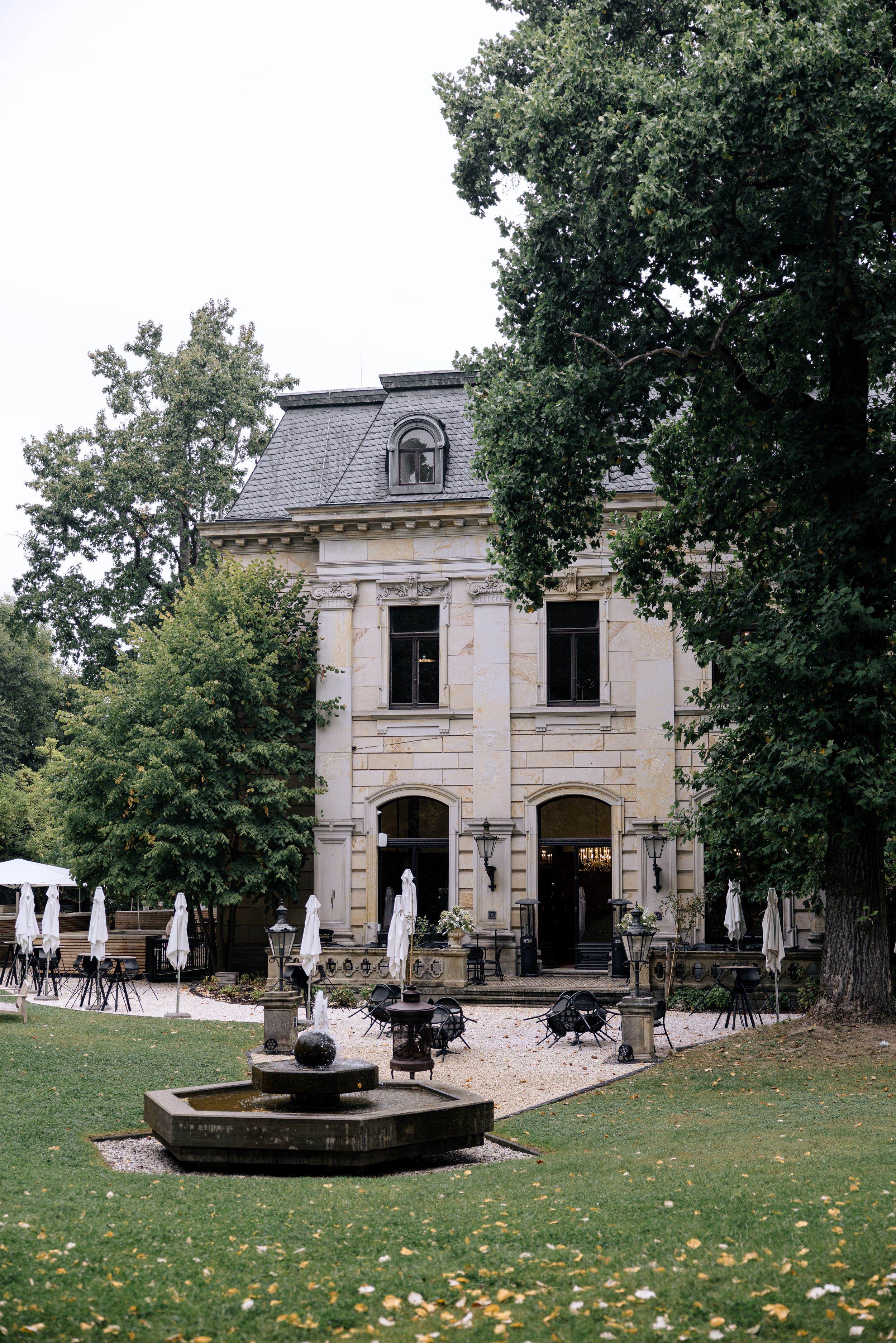 Four connected images show a classic stone mansion with ornate architecture and fountains surrounded by lush trees and lawn.