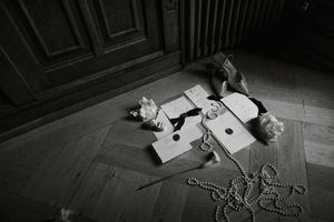 Several small white objects and beads scattered across dark wooden floor surface in dramatic lighting.