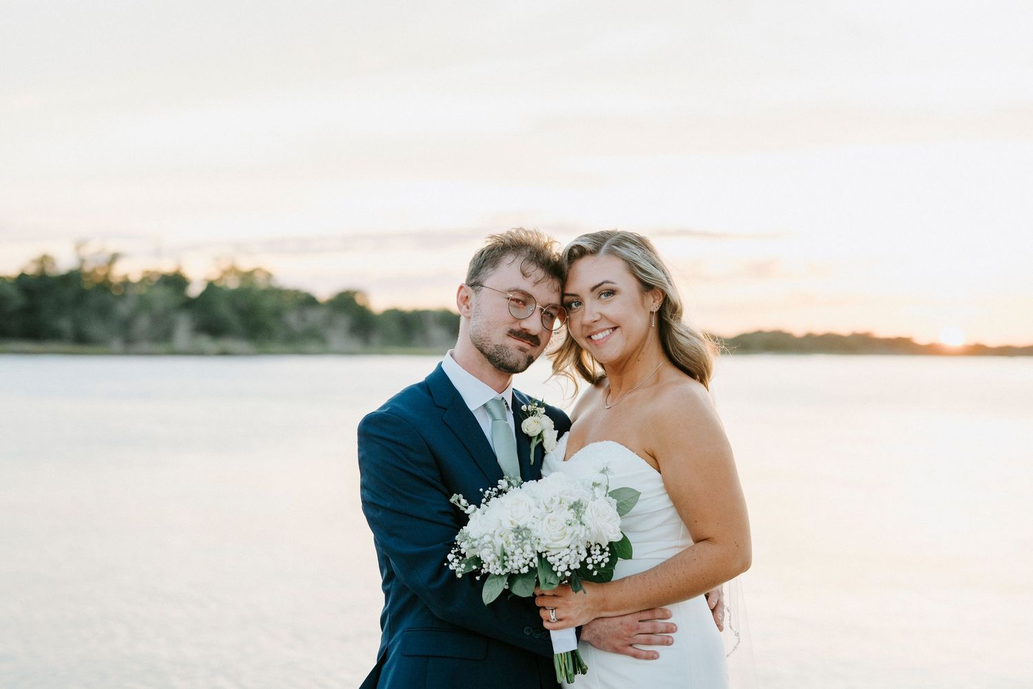 Intimate waterfront wedding portraits at sunset with couple embracing near the marina.