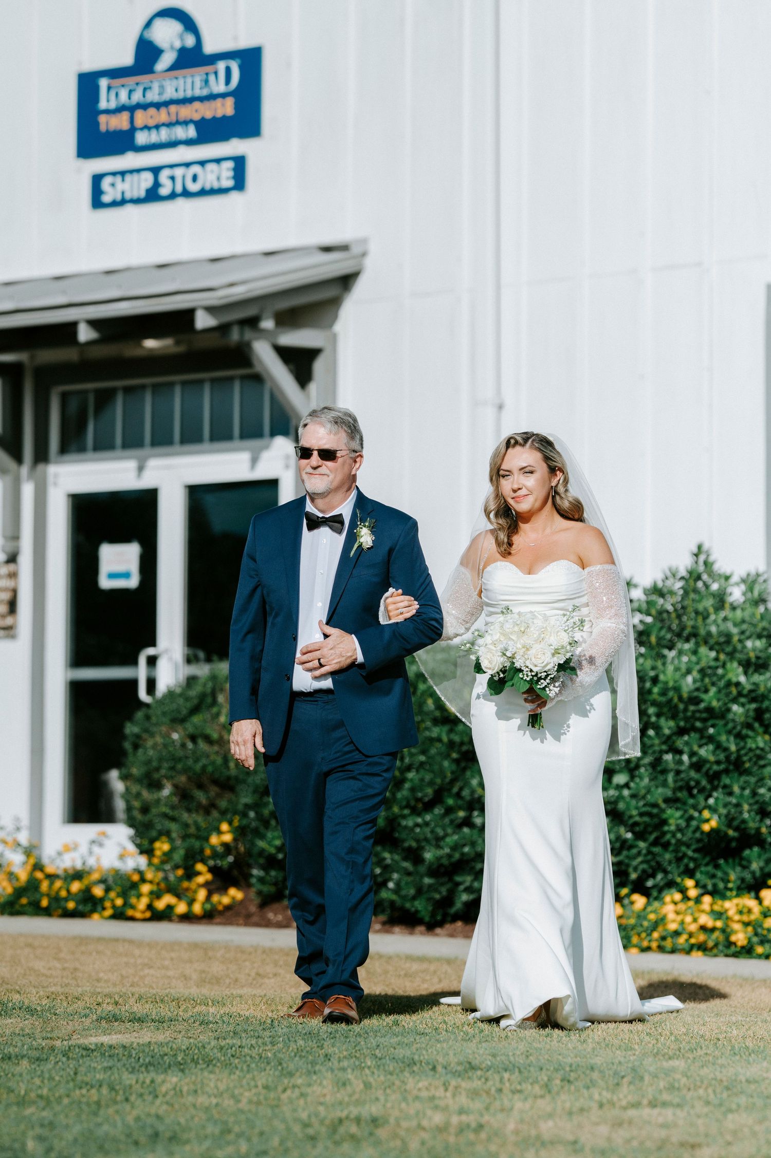 Entrance to Dockside Ship Store with wedding procession walking past yellow flowers.
