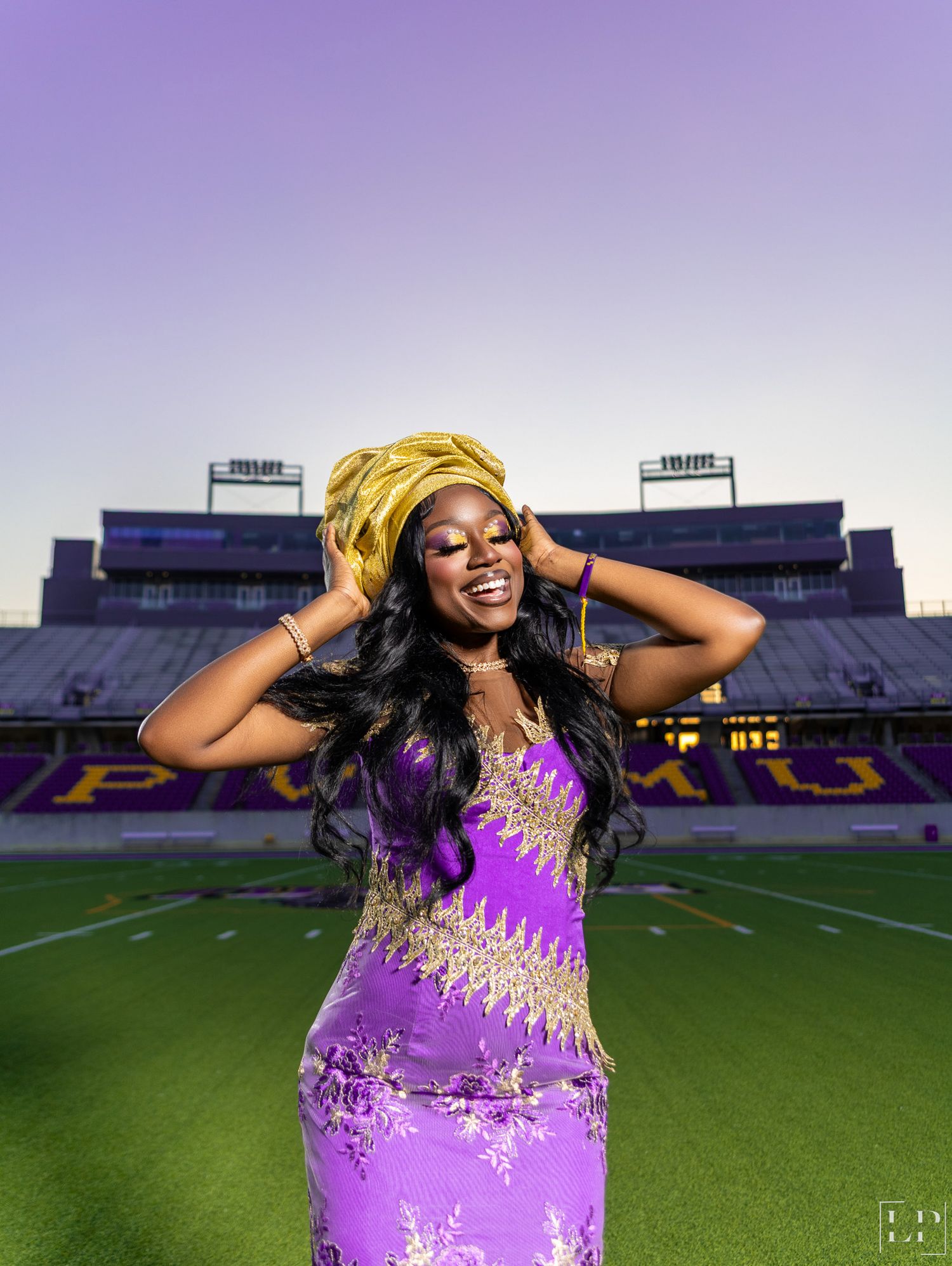 Evening graduation photos on football field featuring purple formal dress.