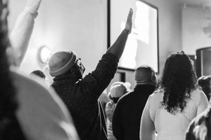 Group of people raising their hands in worship during a church gathering.