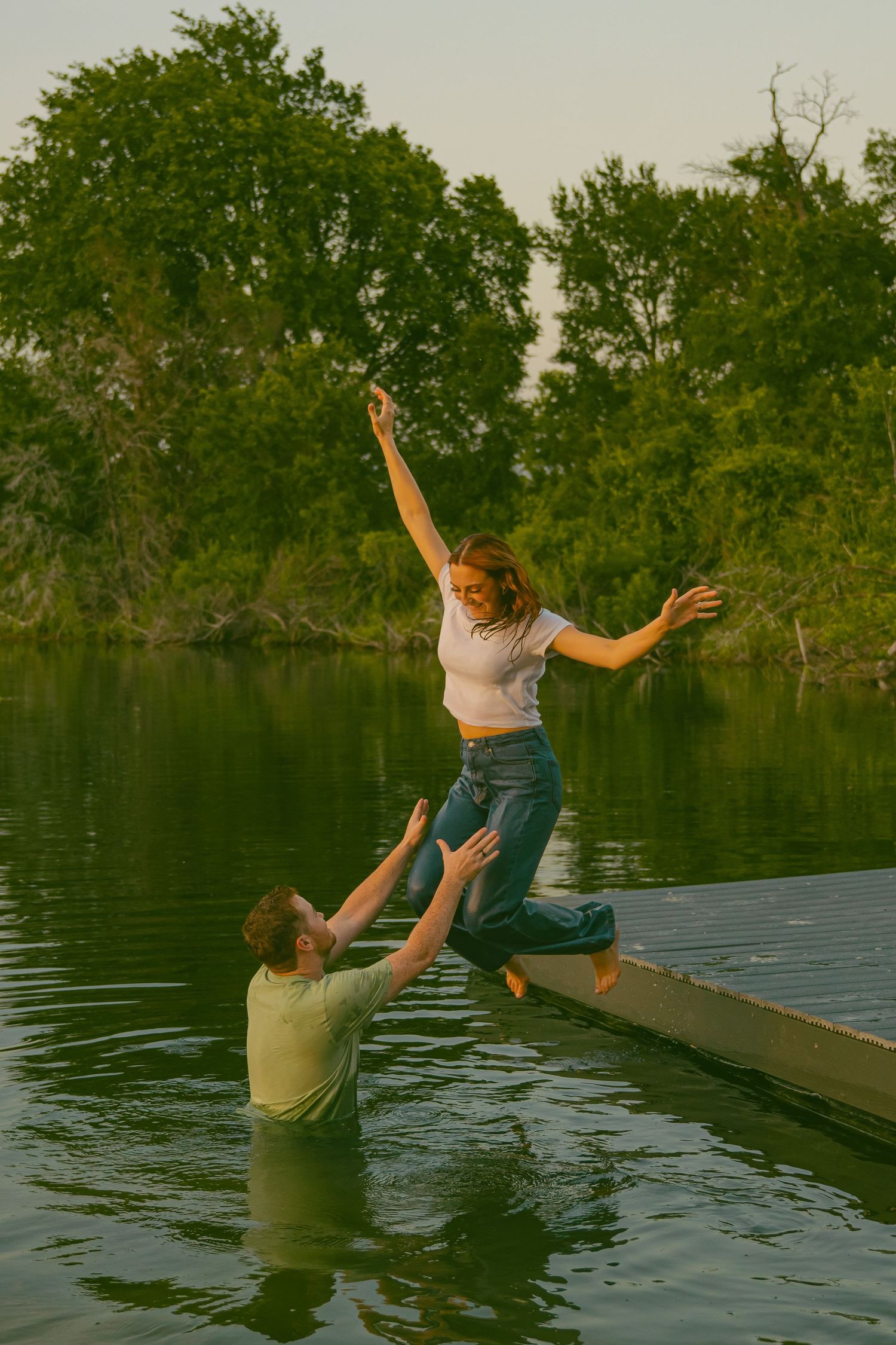 Playful sequence of someone jumping into lake from dock at dusk.