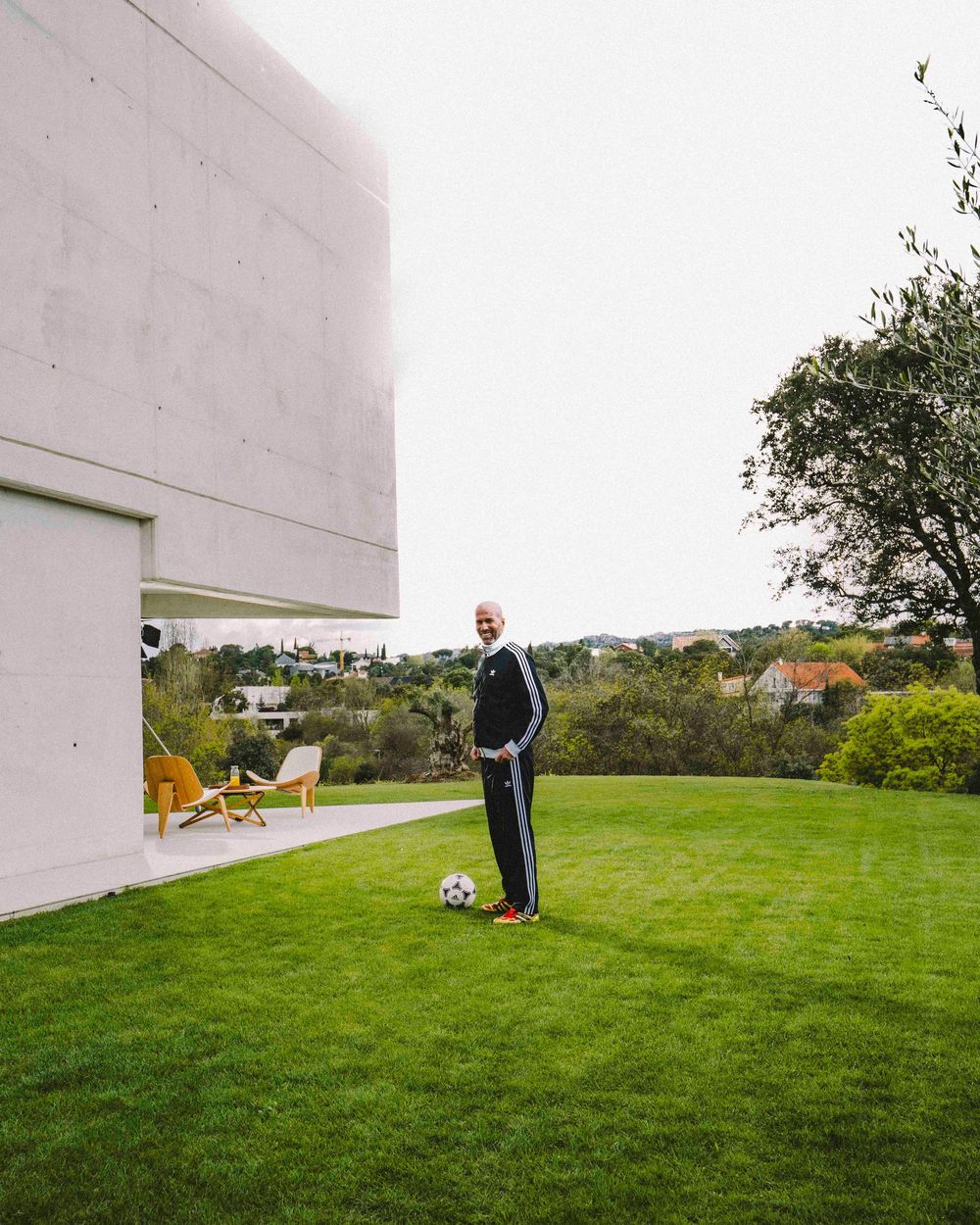 A person stands on a grassy hillside next to a white concrete wall on an overcast day.