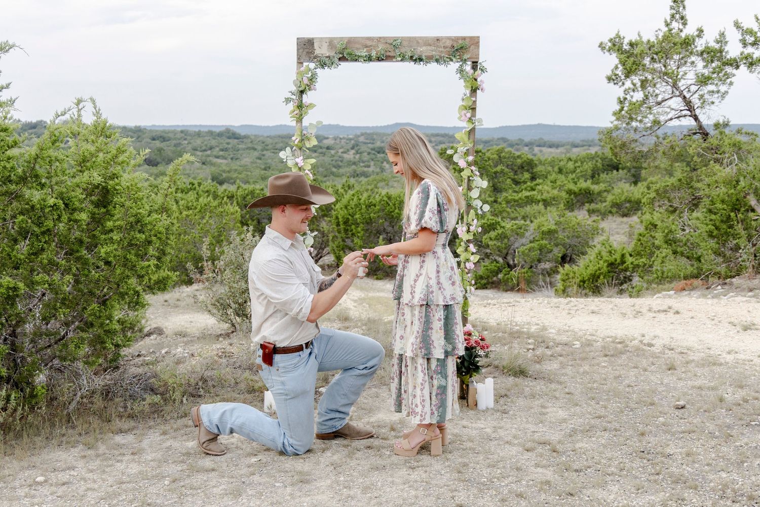 Man proposing to his girlfriend at a candlelit arch during a romantic Dripping Springs Texas proposal.
