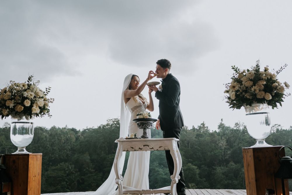 Wedding couple sharing intimate moments at a rustic outdoor reception with floral decorations.