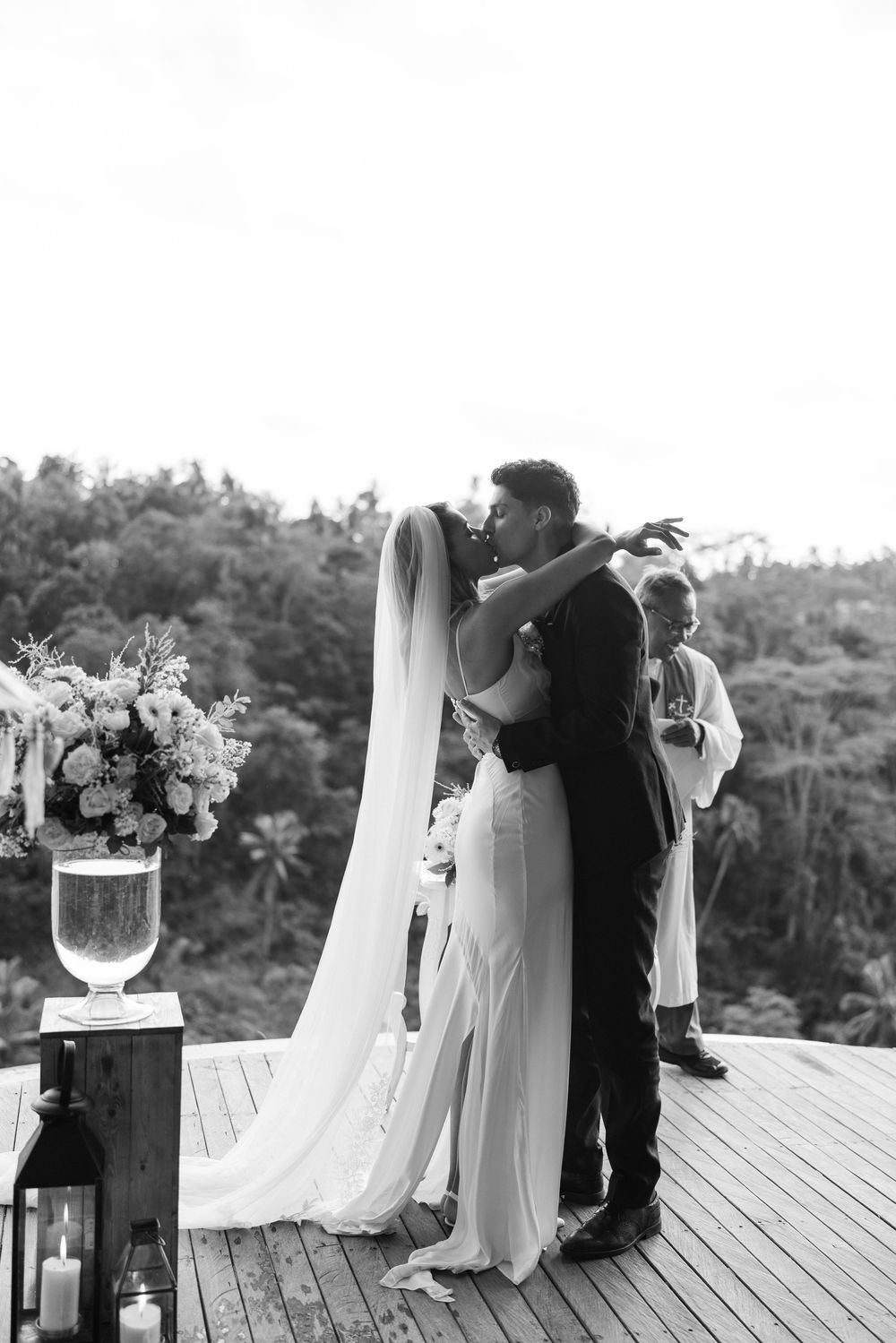 Wedding ceremony on wooden deck overlooking lush forest landscape.