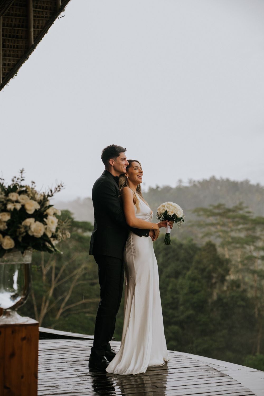 Intimate wedding couple moment on wooden deck with mountain backdrop.