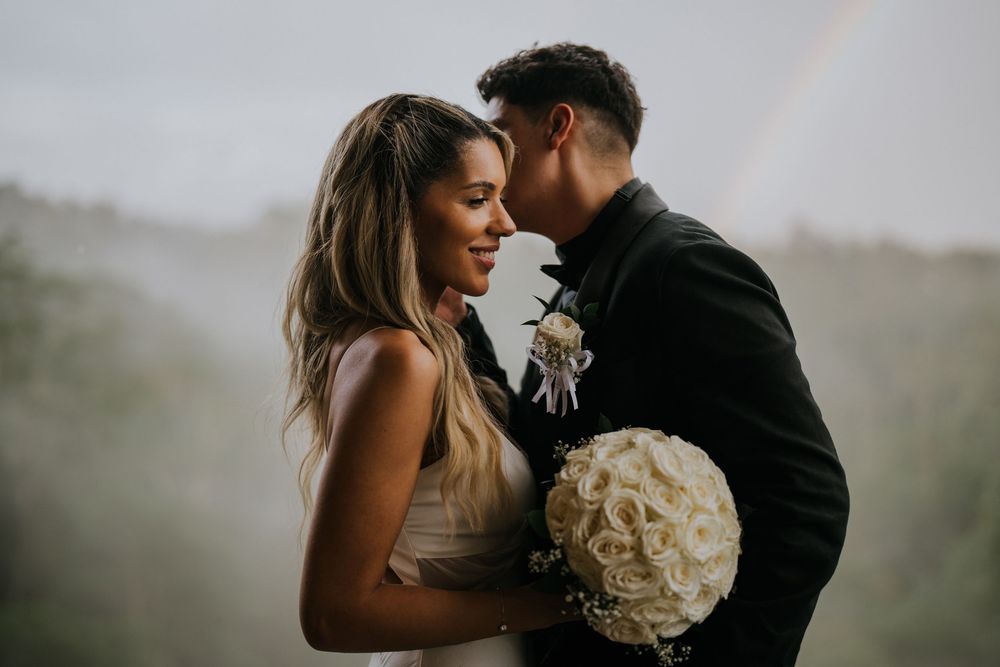 Intimate wedding portraits with white bouquet against misty mountain backdrop.