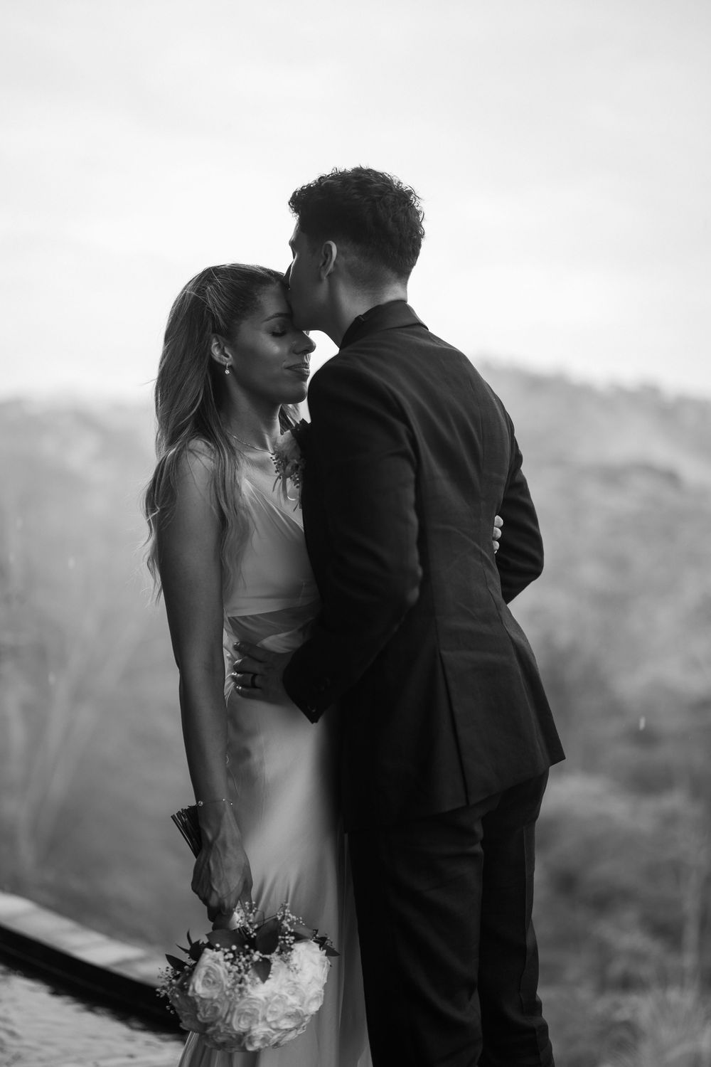 Black and white wedding portrait capturing intimate moment between newlyweds.