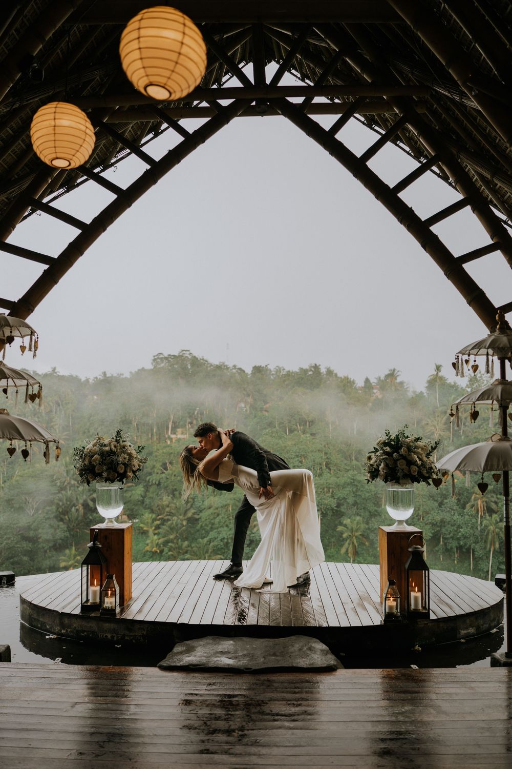 Wedding ceremony setup with paper lanterns and panoramic forest views from wooden deck.