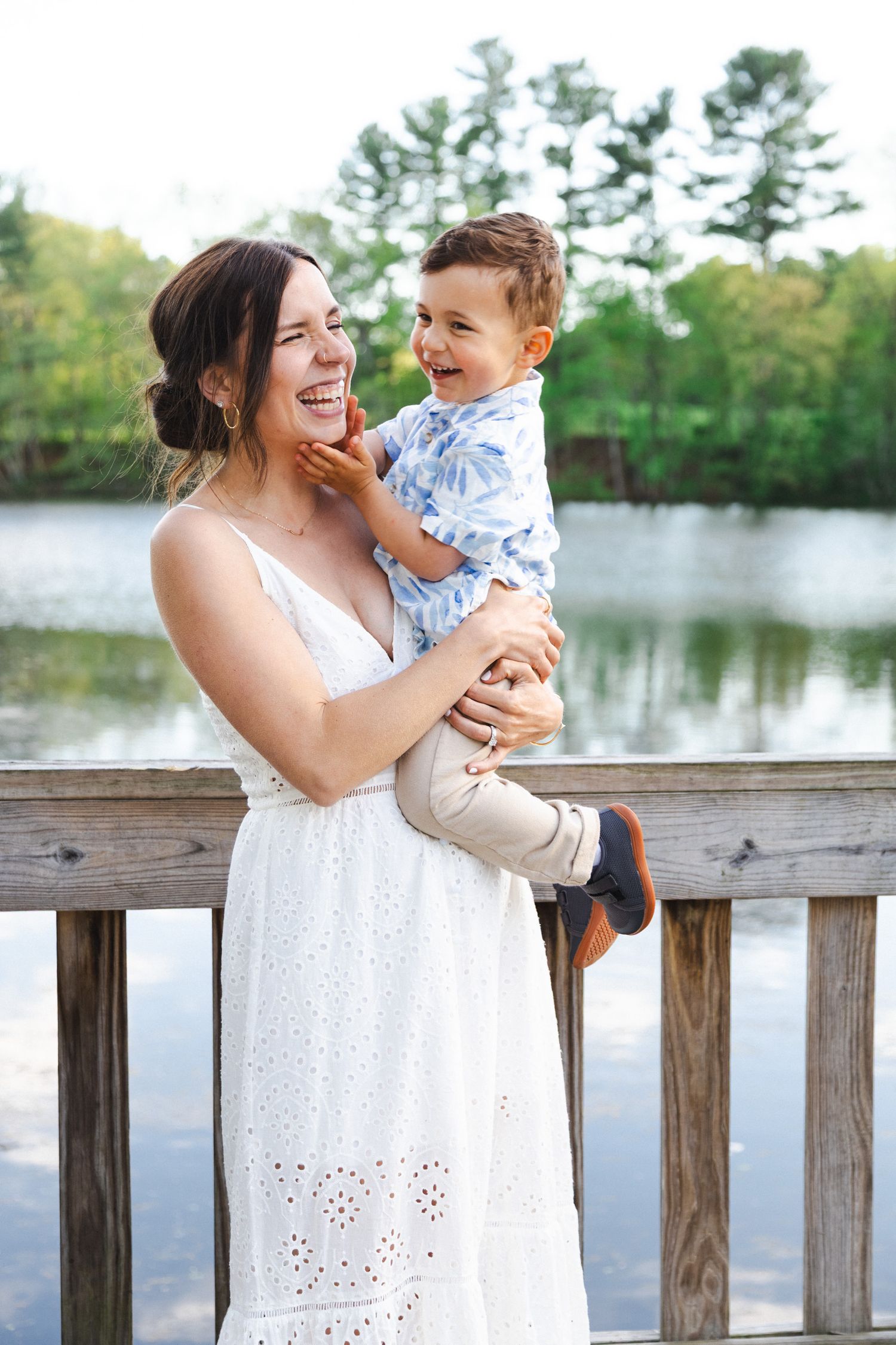 A tender moment shared between parent and child on a wooden dock by a serene lake on a sunny day.