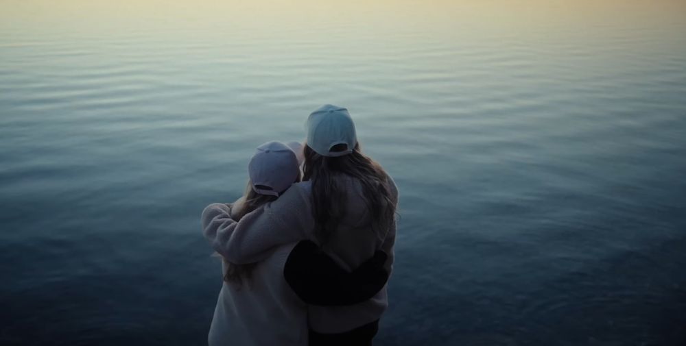 People enjoying a peaceful moment by the water's edge during golden hour.
