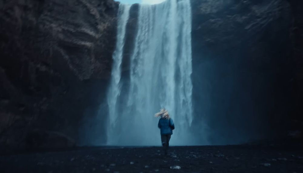 Majestic waterfall cascading down dark rocky cliffs in moody lighting.