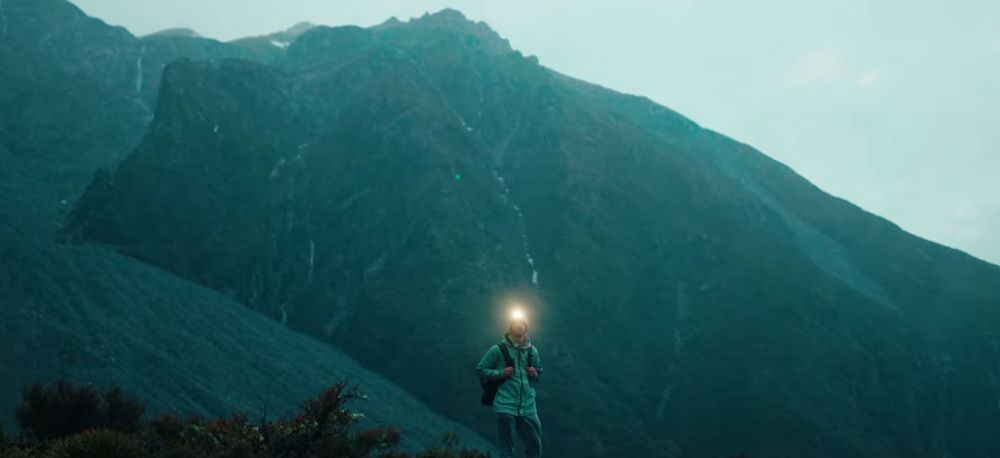 Mountainous landscape with hikers traversing ridge trail at twilight.