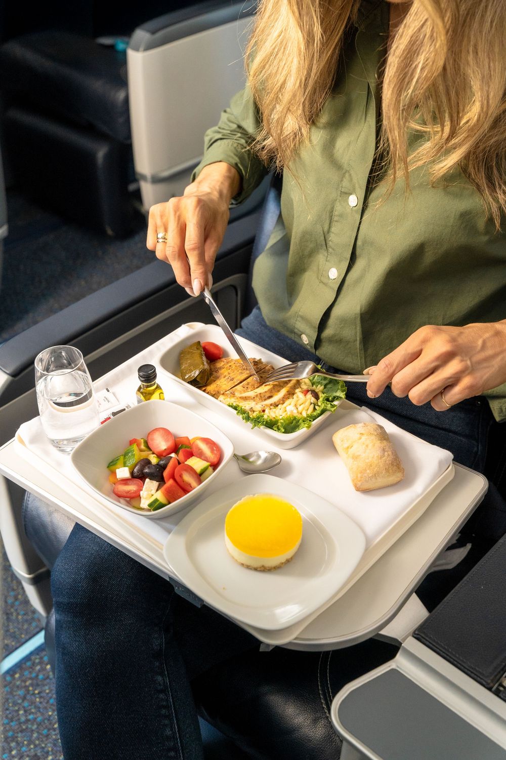 Series of airline meal service photos showing passenger dining on tray tables during flight with bread and salad.