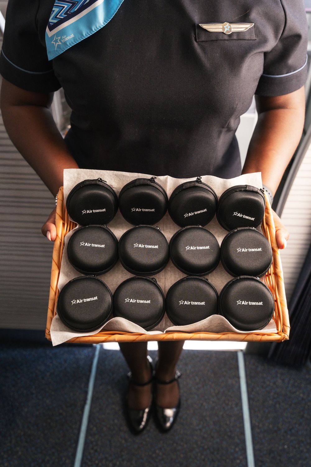 Person holding a tray with four rows of identical black cap hats displaying D.A.S Network branding.