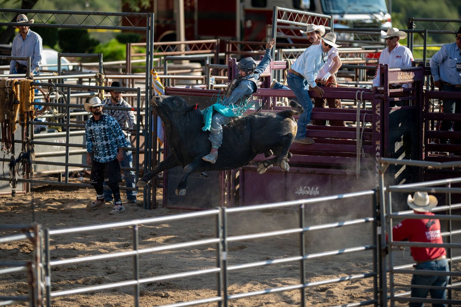 Cowboys gather around a rodeo arena fence during a western competition event.
