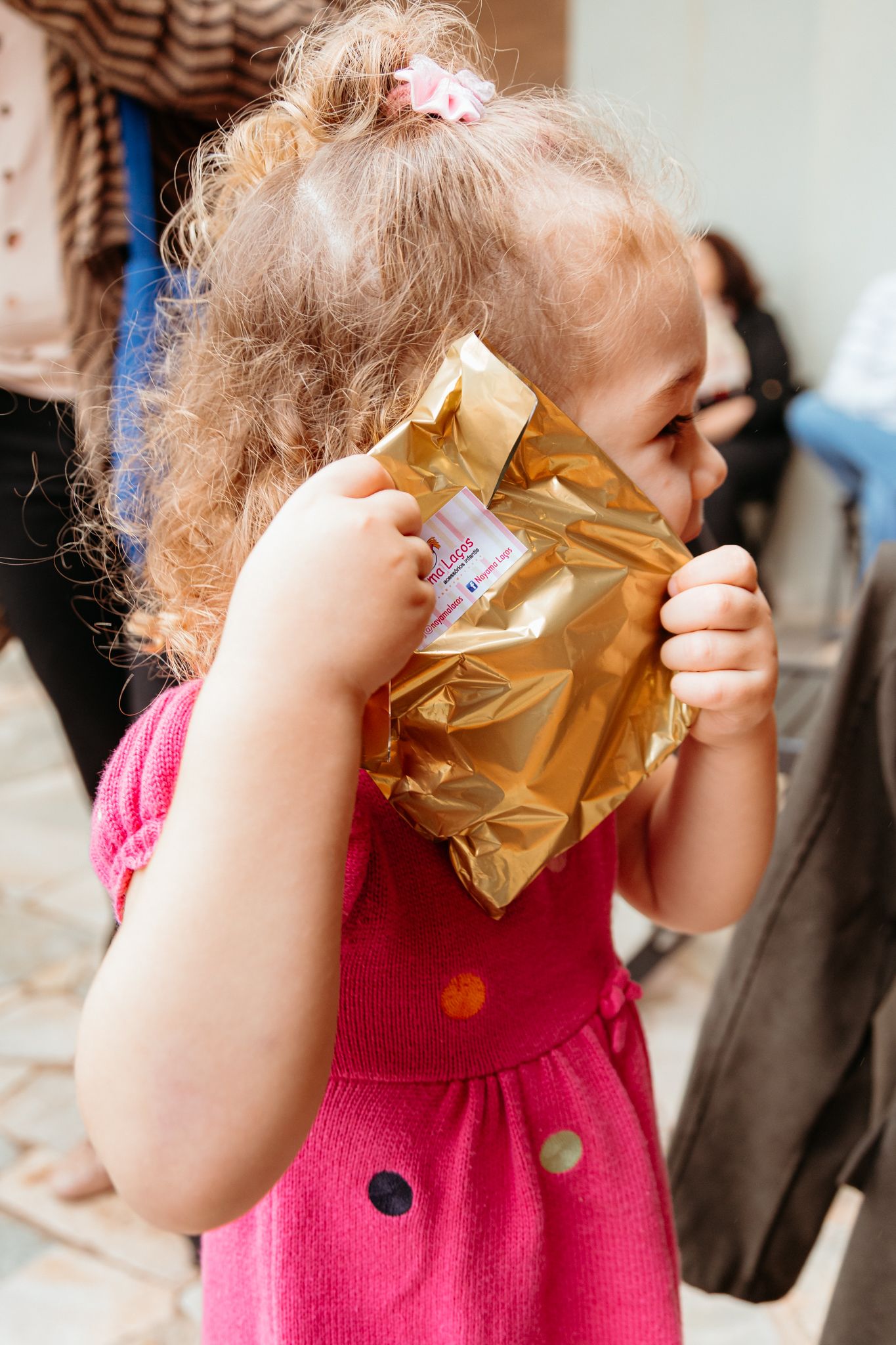 Close-up sequence showing a toddler in pink clothing breathing into a brown paper bag.