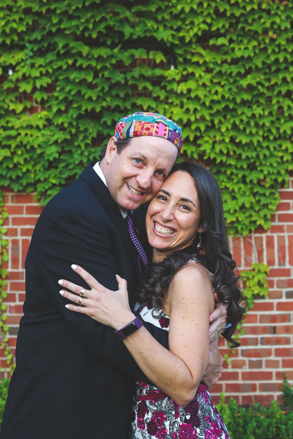 A couple shares joyful embraces against a backdrop of green ivy and brick wall in a series of candid moments.