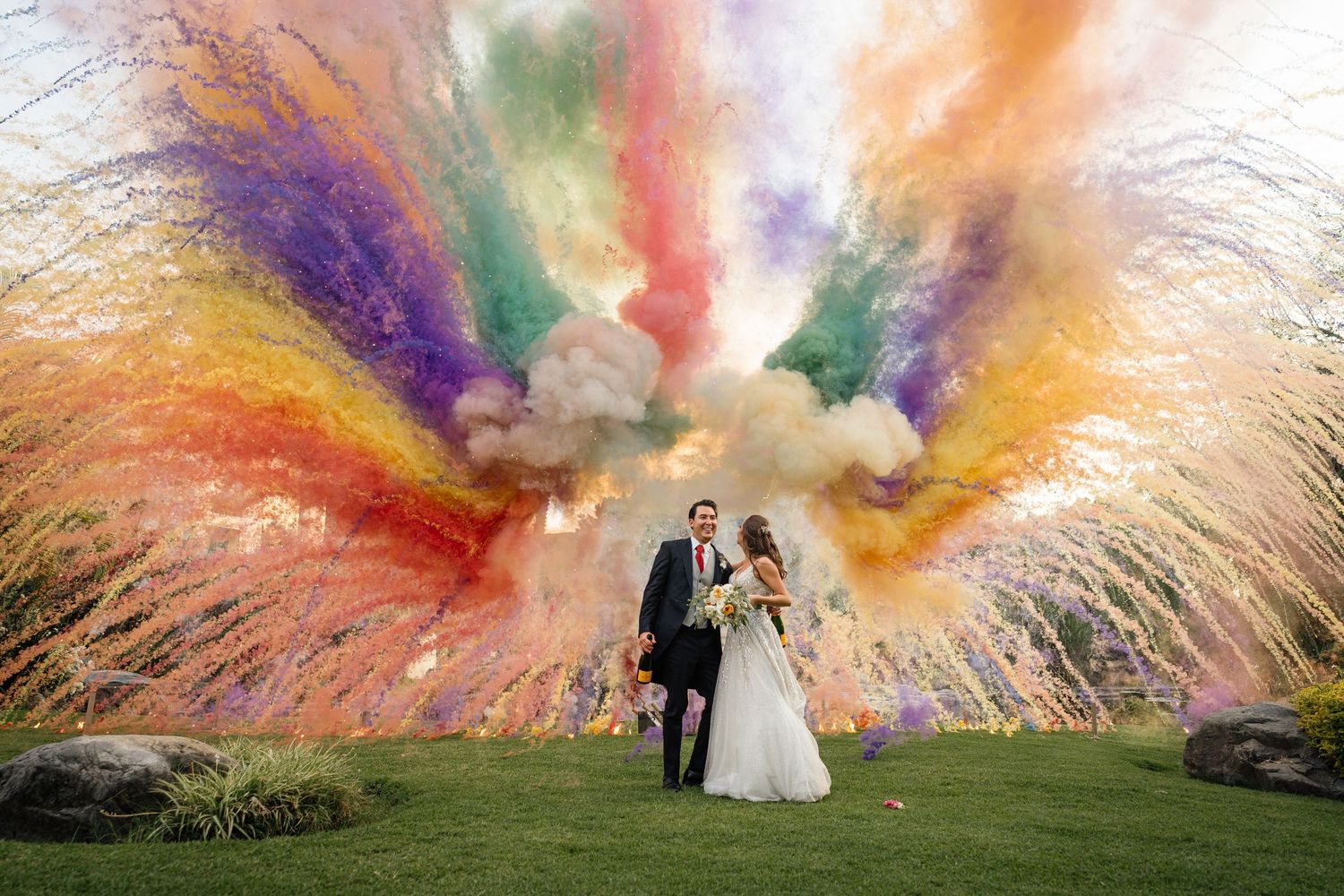 Colorful smoke bomb wedding photos creating vibrant rainbow effects in an outdoor setting.