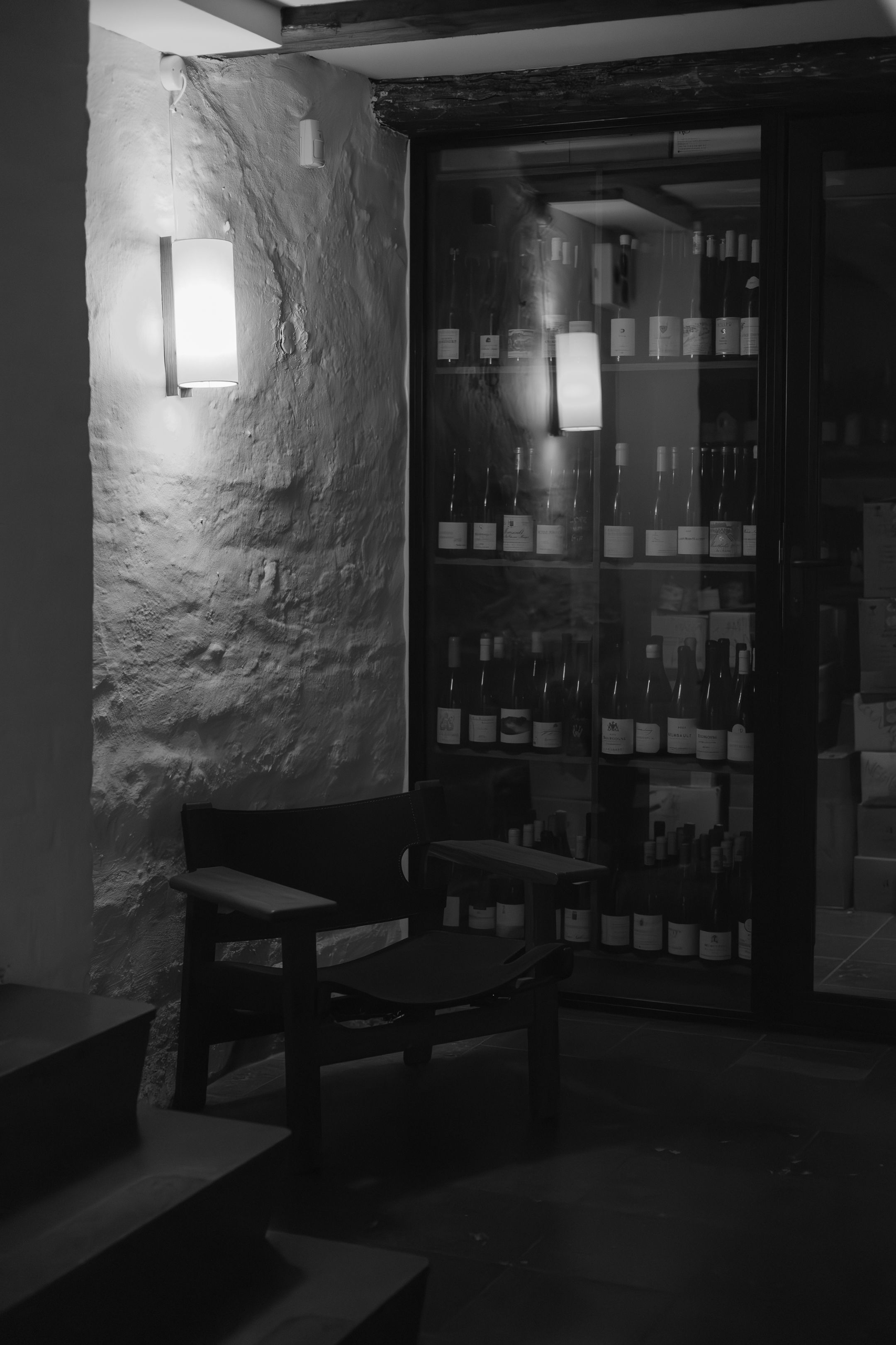 Dark wine cellar interior with stone walls and wooden shelves storing bottles in organized rows.