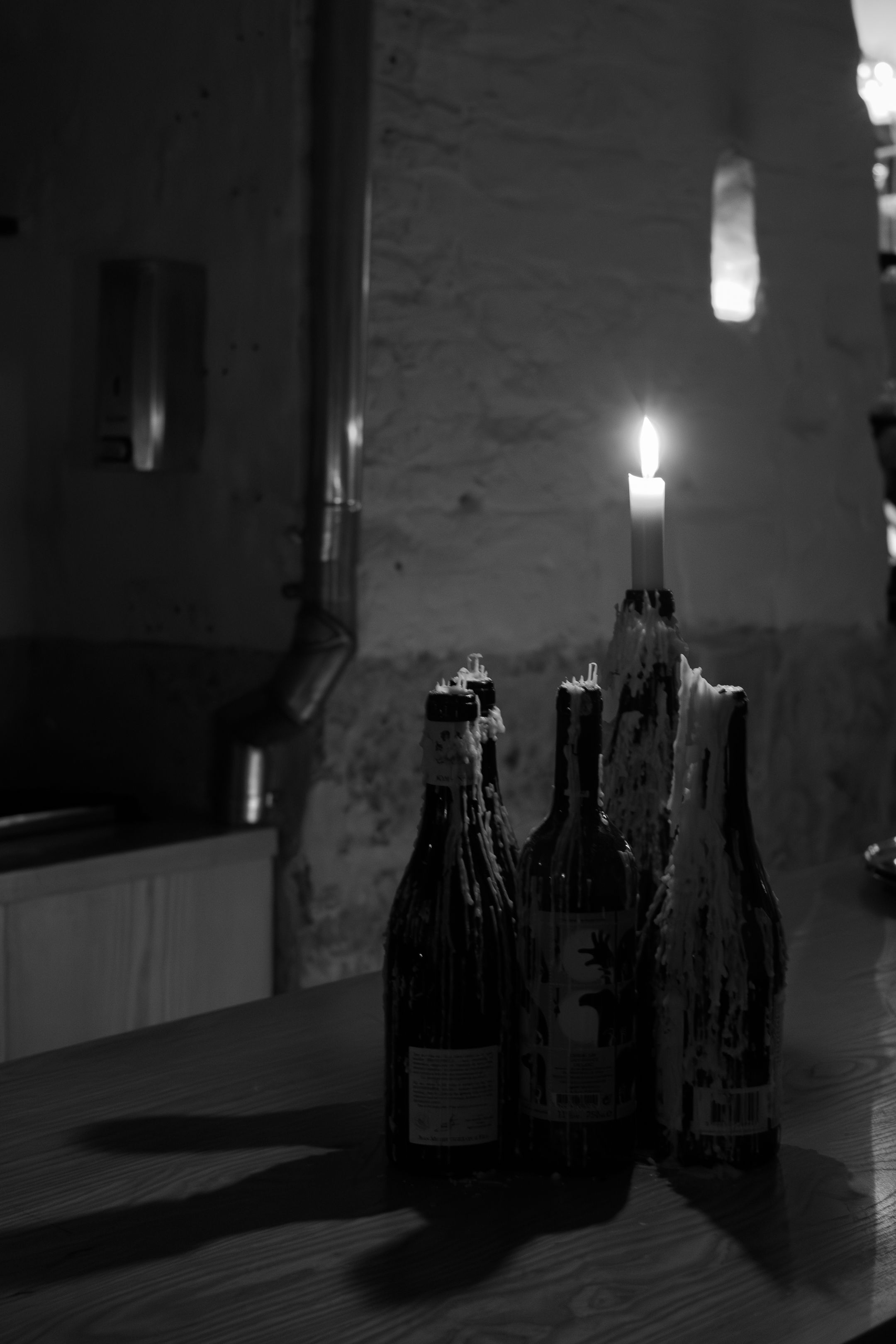 Dark glass bottles arranged in a moody lighting setup creating dramatic shadows and reflections.