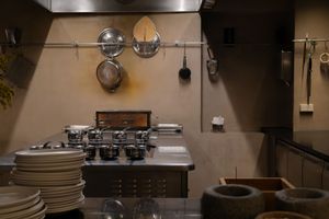 Modern kitchen interior with stainless steel appliances and dark wood cabinets illuminated by pendant lighting.