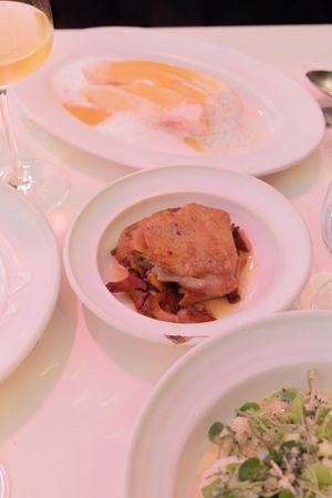 Multiple white plates with food portions arranged on a dining table under warm lighting.