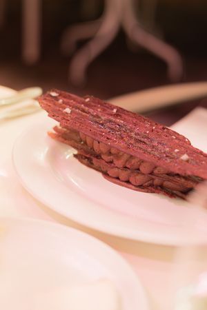 Thinly sliced pieces of medium-rare steak arranged diagonally on a white plate.