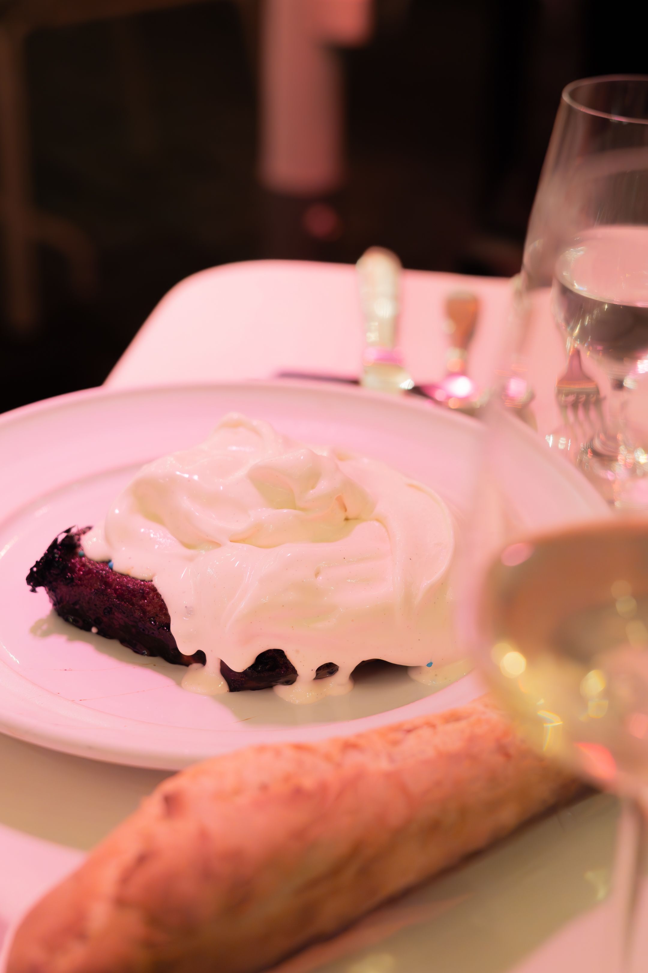 Close-up shot of plated food with pink lighting showing a partially eaten dish on a white plate.