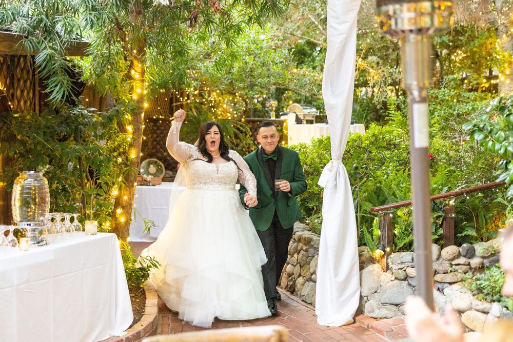 A wedding celebration in a beautiful garden setting with white tablecloths and flowing fabric decorations.