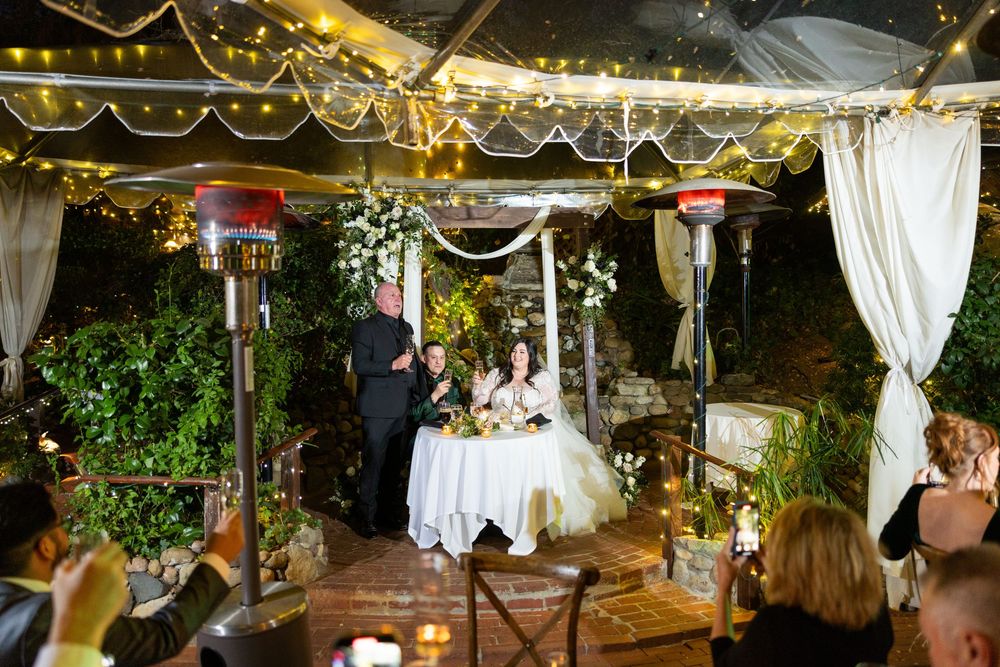 Outdoor wedding venue decorated with string lights and white drapes creating a romantic ambiance.