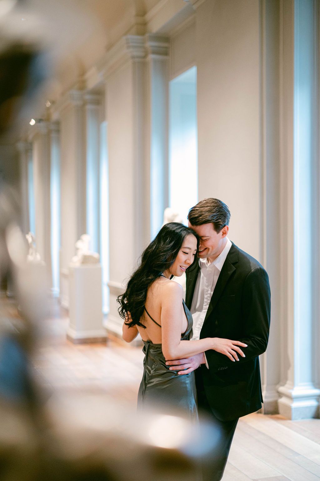 A couple shares intimate moments in a bright hallway with white columns in a collection of romantic wedding photographs.