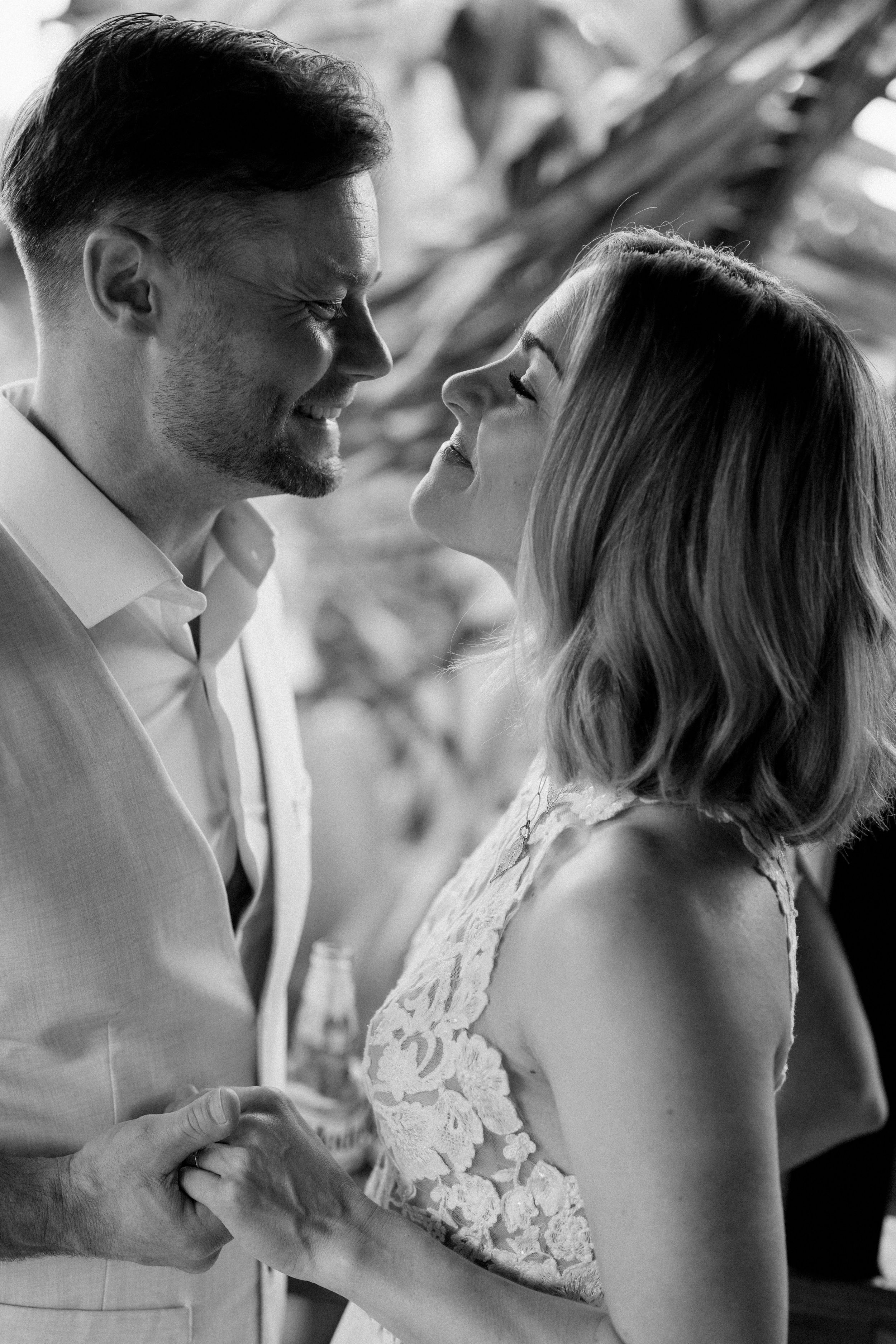 Intimate black and white portrait of a couple in wedding attire sharing a tender moment.