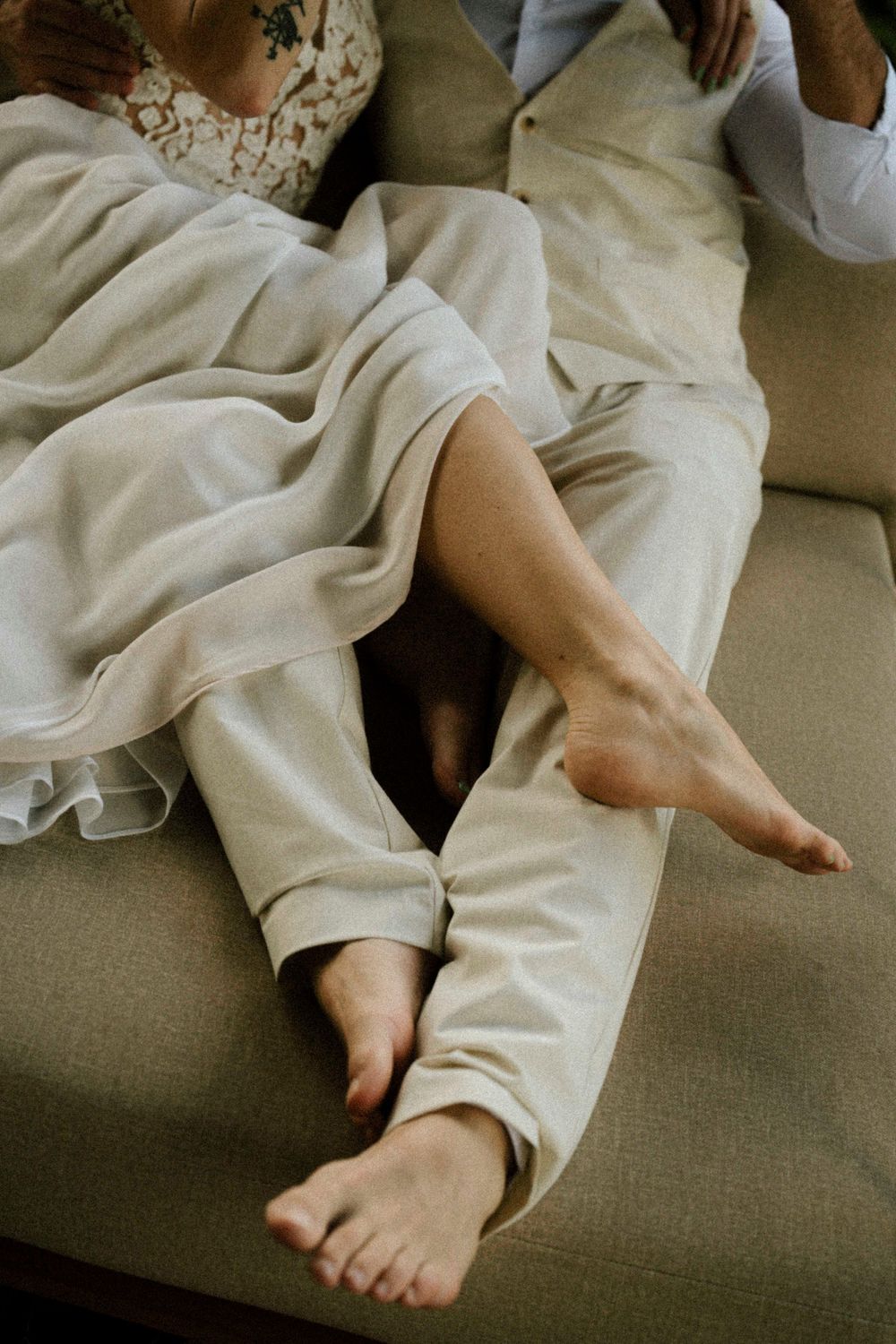 Close-up of bare feet resting on a gray couch with white fabric draping.